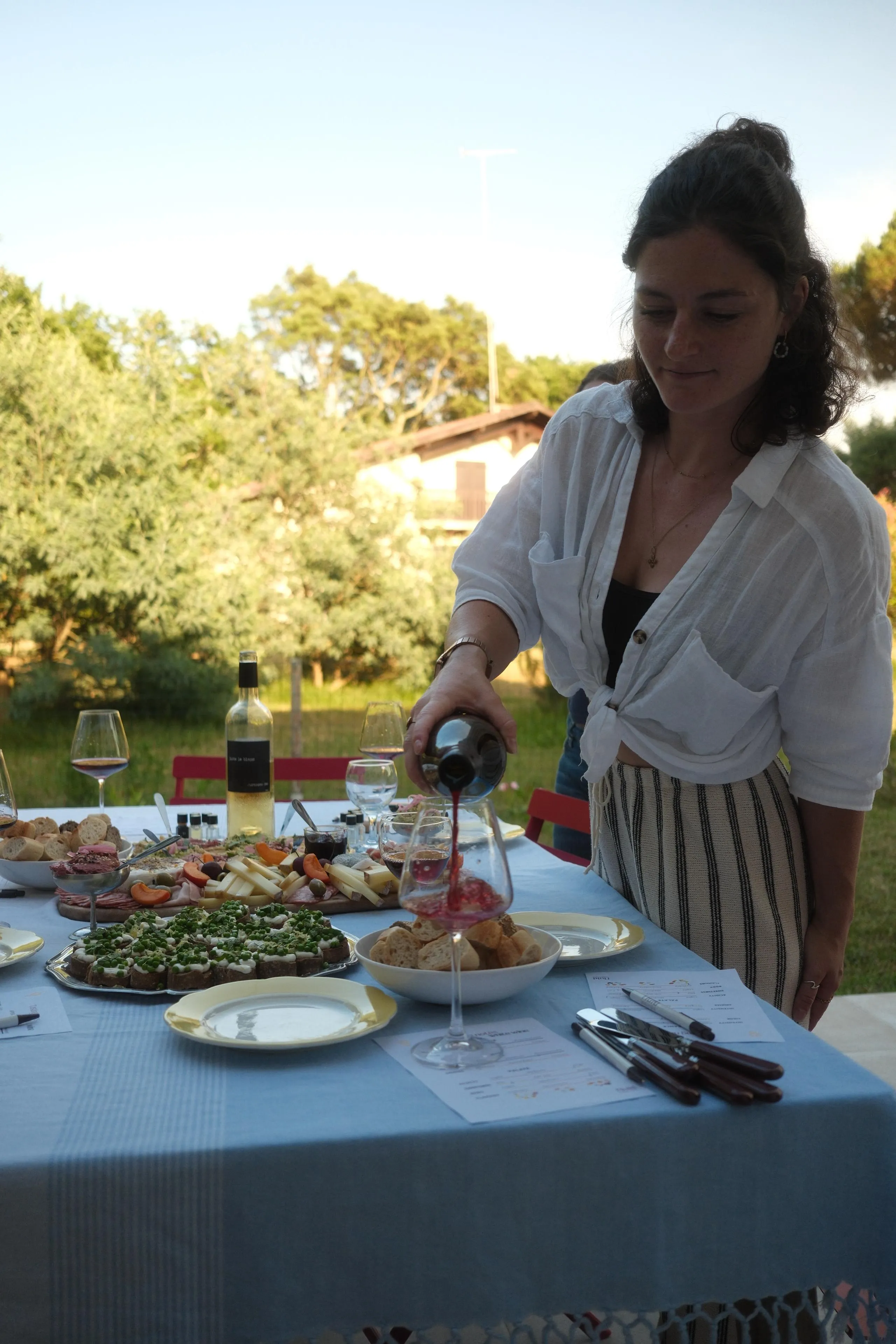 Léa servant un verre de vin rouge lors d'une dégustation en extérieur